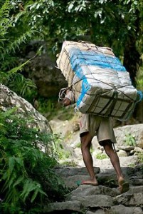 Porter in rural Nepal carrying heavy construction materials.
